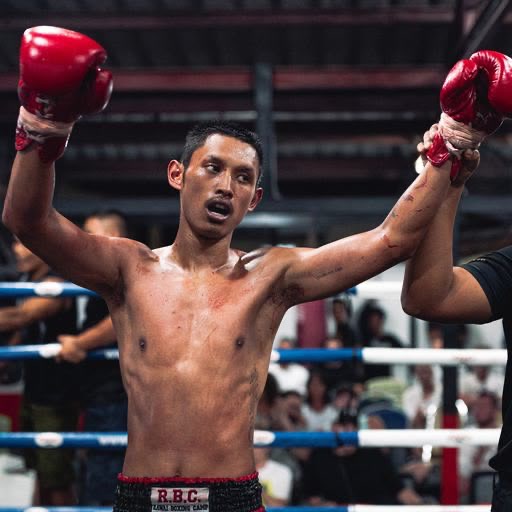 Maimais Muay-Thai-Trainer im Ring, mit erhobenen Boxhandschuhen, Rawai Boxing Camp